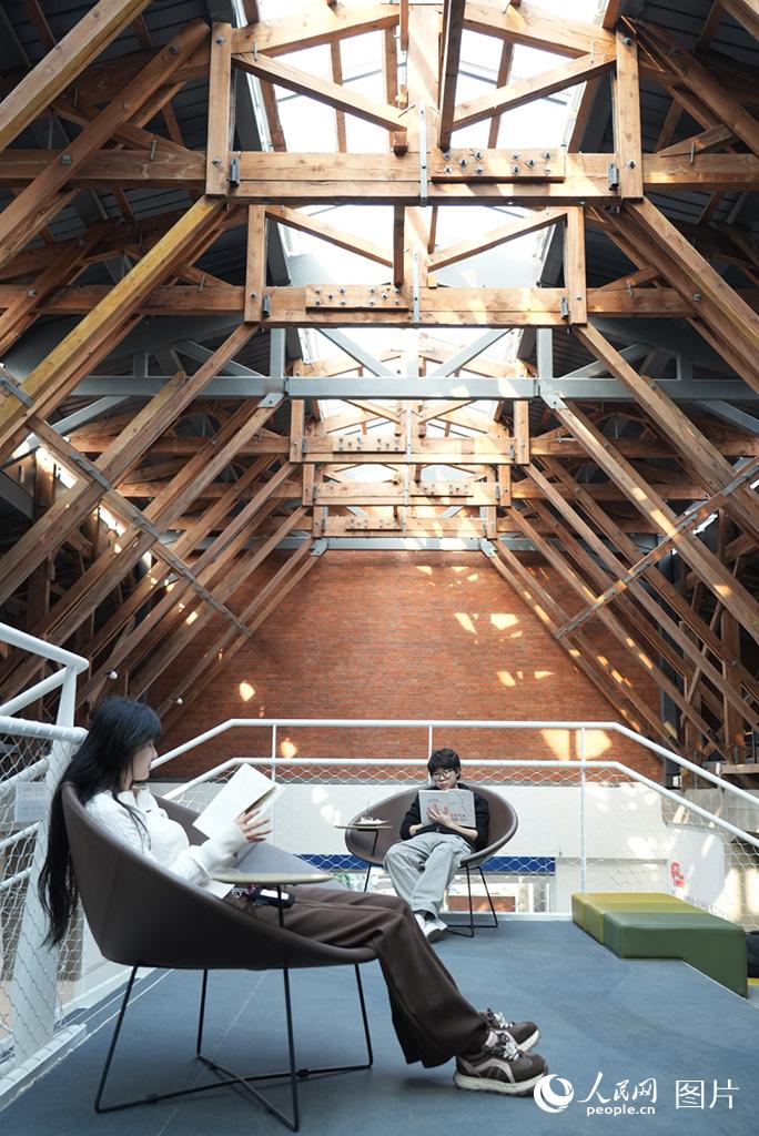 2026年4月15日，在时代文仓城市书房，读者享受阅读的快乐。大东区时代文仓城市书房前身为沈阳东贸库旧址。东贸库是沈城现存建设年代最早、规模最大、保存最完整的民用仓储建筑群，是沈城宝贵的历史工业遗产，对于全国仓储物流业发展史具有重要意义。时代文仓城市书房整体建筑改造于旧东贸库，将历史留下的工业遗产转化为新时代的文化地标。人民网记者 周颂雪摄